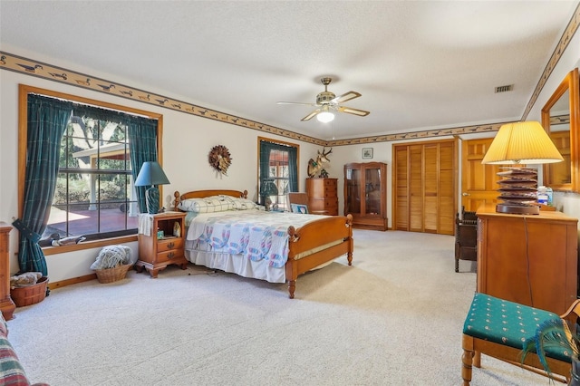 bedroom with light carpet, a textured ceiling, and ceiling fan