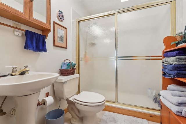 bathroom with sink, a shower with shower door, and toilet