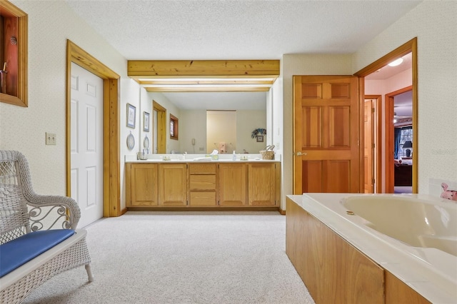 bathroom with a textured ceiling, vanity, and a bath