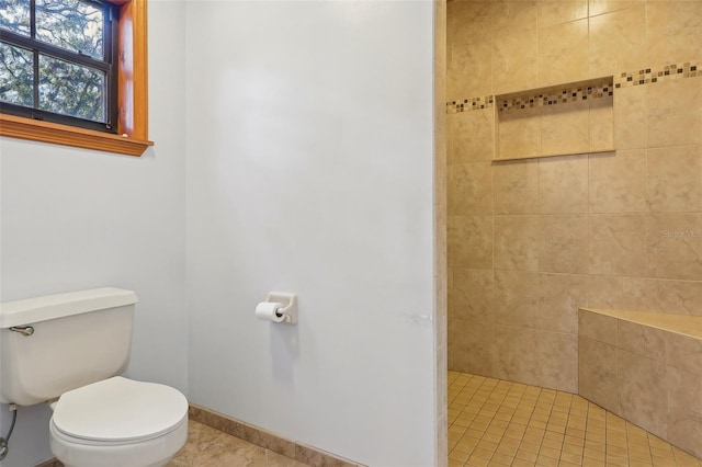 bathroom featuring tile patterned floors, toilet, and tiled shower