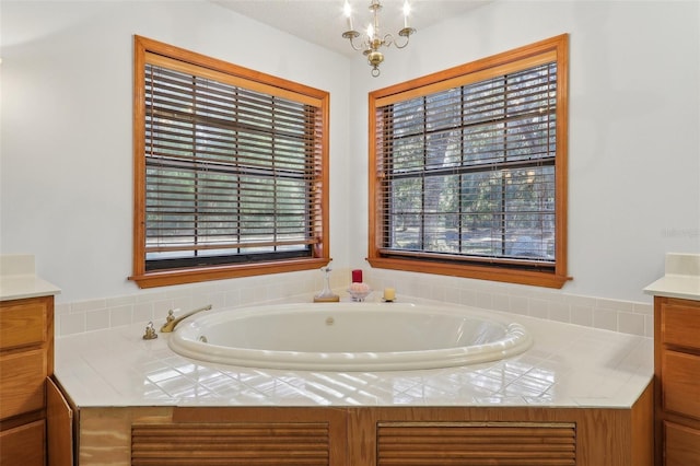 bathroom with a bathing tub, a chandelier, vanity, and a healthy amount of sunlight