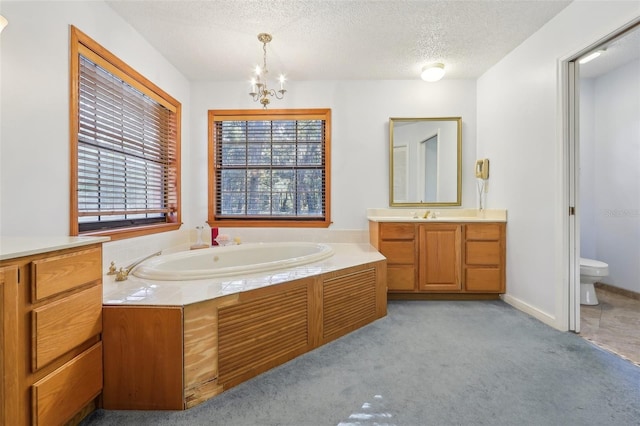 bathroom featuring a washtub, an inviting chandelier, a textured ceiling, toilet, and vanity