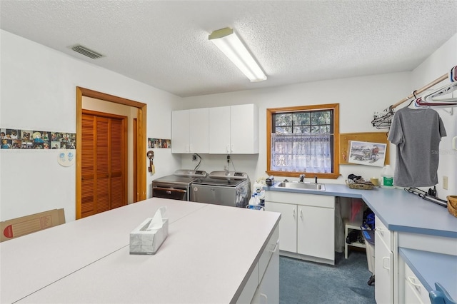 kitchen with white cabinets, a textured ceiling, and washing machine and clothes dryer