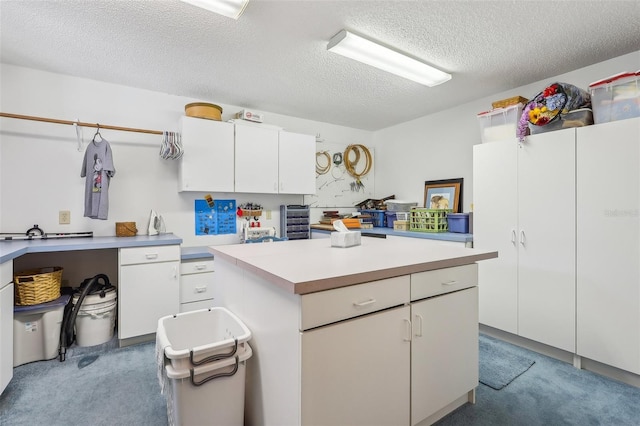 kitchen with white cabinetry, a center island, carpet, and a textured ceiling