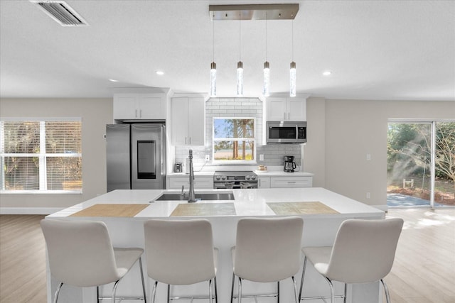 kitchen with sink, a center island with sink, white cabinets, and appliances with stainless steel finishes