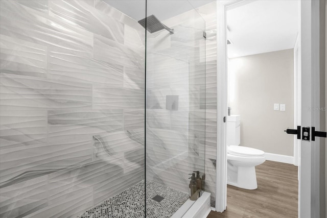 bathroom featuring toilet, hardwood / wood-style floors, and tiled shower