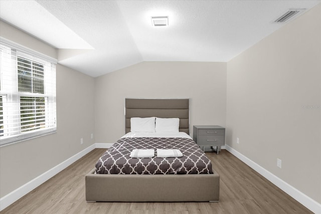 bedroom with wood-type flooring and vaulted ceiling