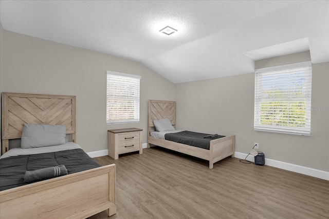 bedroom with wood-type flooring, lofted ceiling, and a textured ceiling