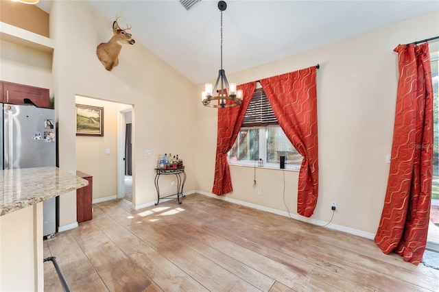 unfurnished dining area with an inviting chandelier and light hardwood / wood-style flooring