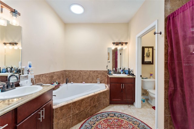 bathroom featuring tiled bath, tile patterned floors, vanity, and toilet