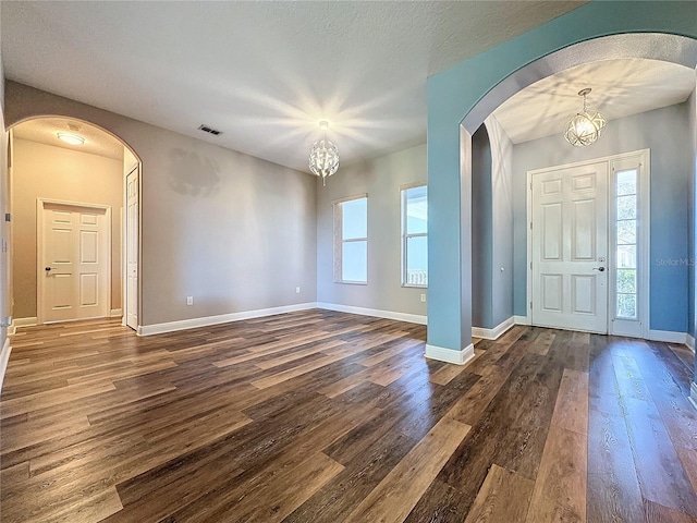 foyer with a textured ceiling, dark wood-type flooring, and a notable chandelier