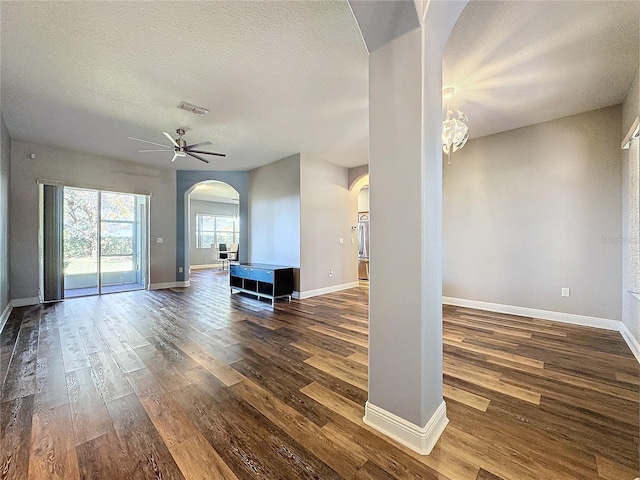 unfurnished living room featuring ceiling fan, dark wood-type flooring, and a textured ceiling