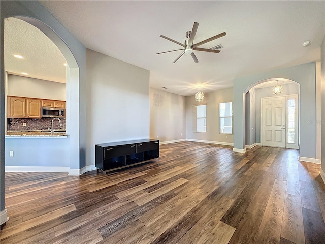 unfurnished living room with dark hardwood / wood-style flooring, ceiling fan, sink, and a textured ceiling