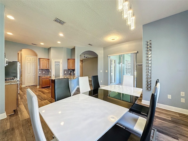 dining room with a textured ceiling, ceiling fan, and wood-type flooring