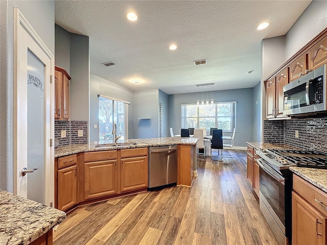 kitchen featuring a wealth of natural light, light hardwood / wood-style floors, sink, appliances with stainless steel finishes, and pendant lighting