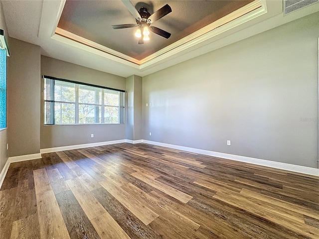 empty room featuring ceiling fan, wood-type flooring, and a raised ceiling