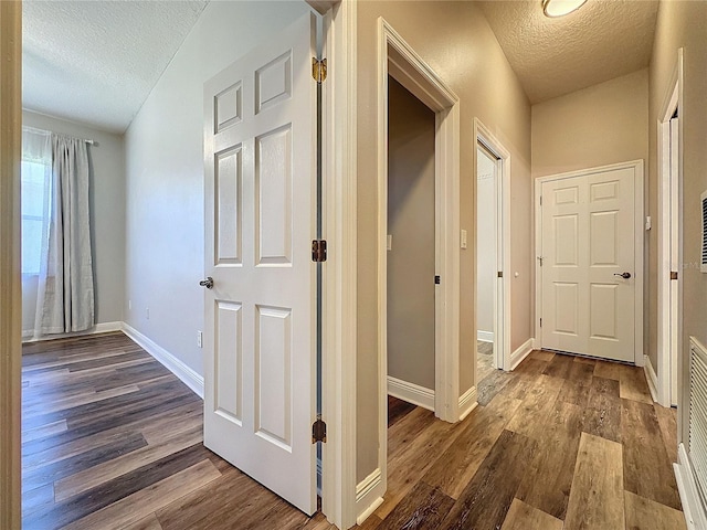 corridor featuring a textured ceiling and dark hardwood / wood-style floors