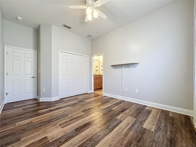 unfurnished bedroom with ceiling fan, a closet, dark hardwood / wood-style flooring, and a textured ceiling