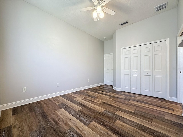 unfurnished bedroom with a textured ceiling, dark wood-type flooring, ceiling fan, and a closet