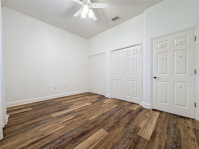 unfurnished bedroom featuring ceiling fan, two closets, and dark hardwood / wood-style floors