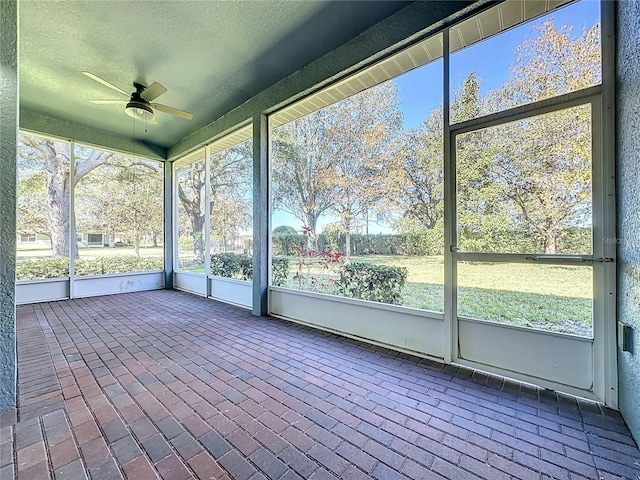 unfurnished sunroom featuring ceiling fan and a healthy amount of sunlight