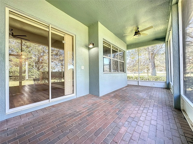 unfurnished sunroom with ceiling fan