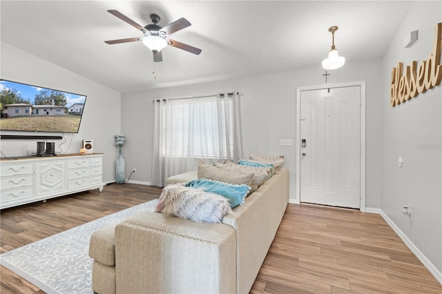 living room featuring lofted ceiling, a textured ceiling, ceiling fan, and light hardwood / wood-style floors