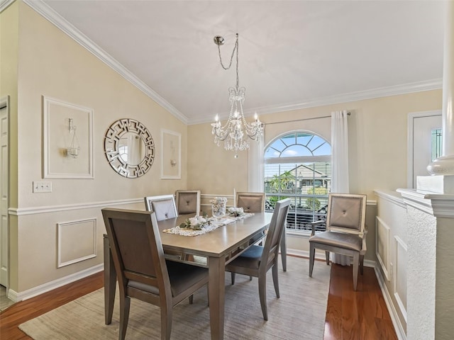 dining room with hardwood / wood-style floors, crown molding, a chandelier, and vaulted ceiling