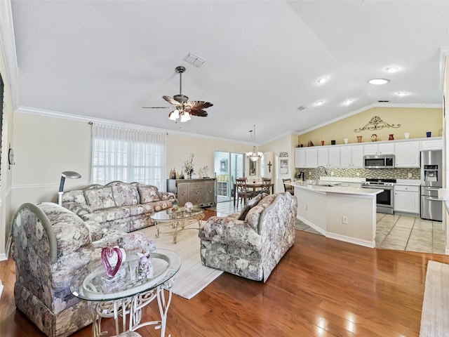 living room with light hardwood / wood-style flooring, vaulted ceiling, ceiling fan, sink, and ornamental molding