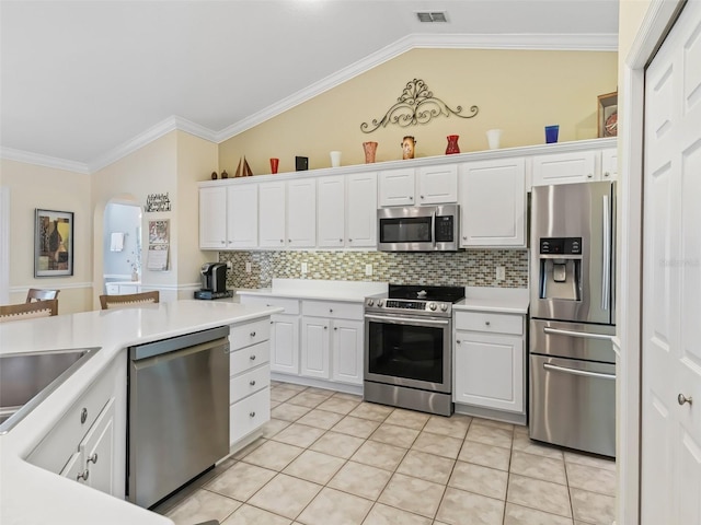 kitchen featuring crown molding, appliances with stainless steel finishes, white cabinetry, decorative backsplash, and lofted ceiling