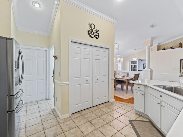 kitchen with stainless steel refrigerator with ice dispenser, sink, white cabinets, and crown molding