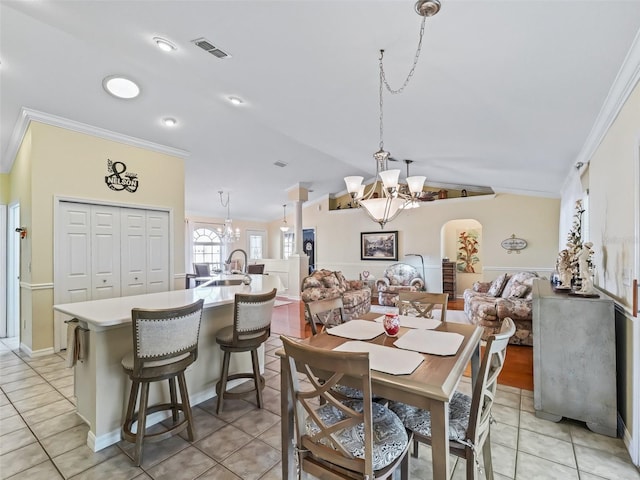 dining area with sink, light tile patterned floors, ornamental molding, and an inviting chandelier