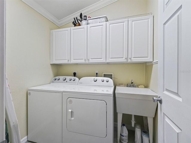 clothes washing area featuring washing machine and clothes dryer, crown molding, and cabinets