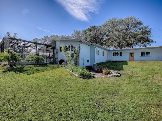 back of property with glass enclosure and a yard