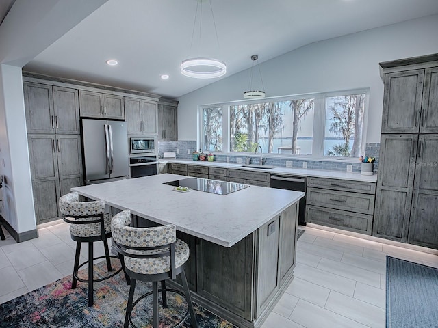 kitchen featuring hanging light fixtures, sink, tasteful backsplash, a center island, and black appliances