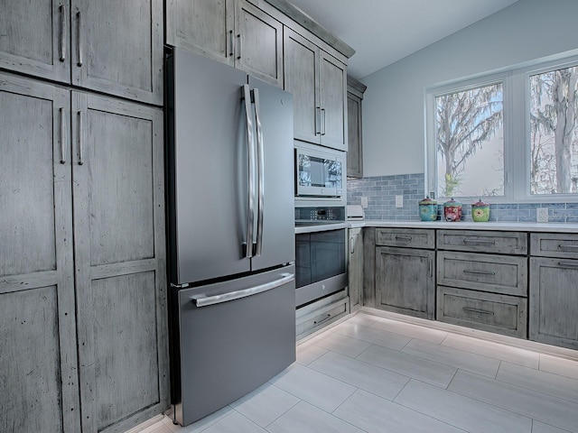 kitchen with stainless steel appliances, vaulted ceiling, and tasteful backsplash