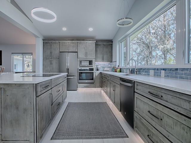 kitchen featuring appliances with stainless steel finishes, decorative light fixtures, light tile patterned floors, decorative backsplash, and lofted ceiling