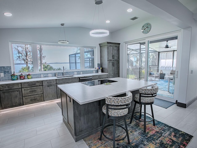 kitchen with hanging light fixtures, sink, a kitchen island, backsplash, and a breakfast bar area