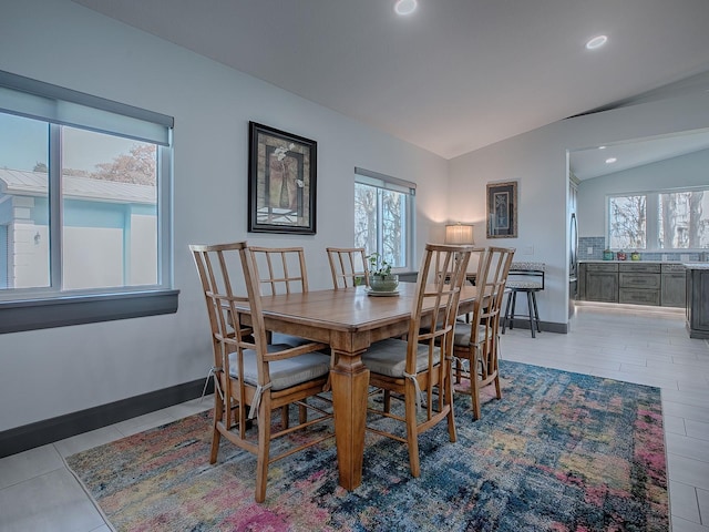 dining space with light tile patterned floors and lofted ceiling