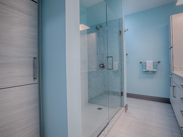 bathroom with a shower with door, vanity, and tile patterned flooring