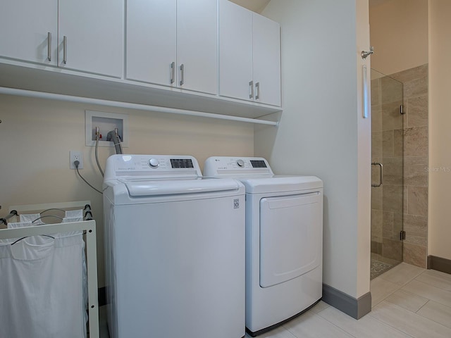 laundry room with cabinets, light tile patterned floors, and washing machine and clothes dryer