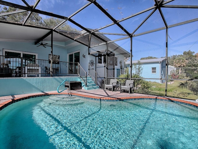 view of pool featuring glass enclosure, ceiling fan, and a patio