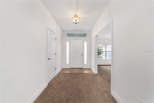 carpeted entrance foyer featuring an inviting chandelier