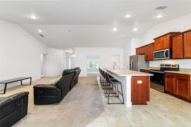 kitchen featuring sink, a kitchen island with sink, stainless steel appliances, a kitchen breakfast bar, and light tile patterned flooring