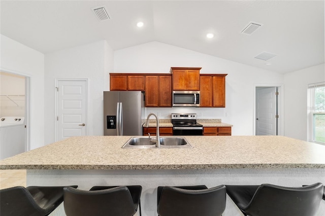 kitchen with sink, stainless steel appliances, an island with sink, and a kitchen bar