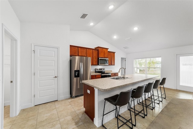 kitchen featuring vaulted ceiling, an island with sink, sink, a kitchen breakfast bar, and stainless steel appliances