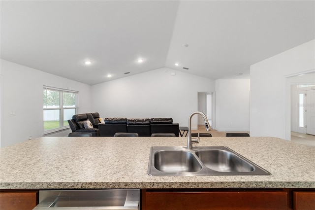 kitchen featuring vaulted ceiling, a kitchen island with sink, dishwasher, and sink