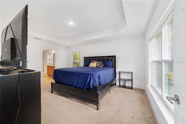 bedroom featuring light carpet, a tray ceiling, crown molding, and ensuite bathroom