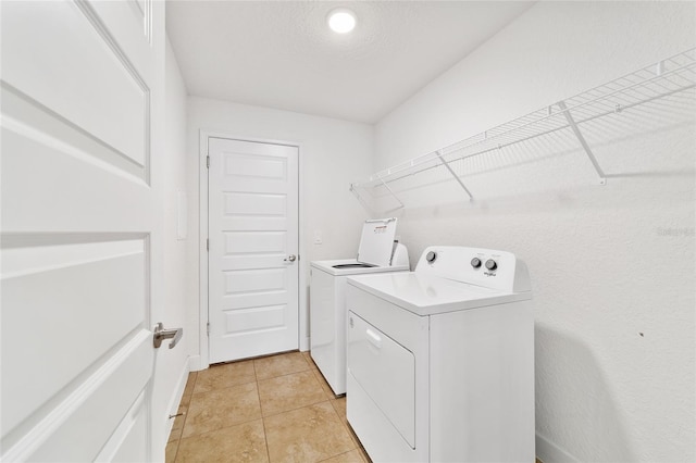 laundry room featuring light tile patterned flooring, washing machine and dryer, and a textured ceiling