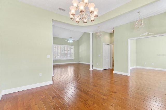 unfurnished room with high vaulted ceiling, hardwood / wood-style flooring, ceiling fan with notable chandelier, and decorative columns